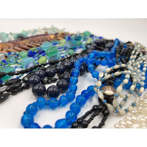 1103 - A collection of beaded necklaces to include foiled glass, carved teak etc.