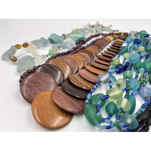 1103 - A collection of beaded necklaces to include foiled glass, carved teak etc.