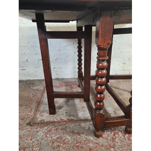 11 - An 18th century oak drop leaf gate leg dining table with bobbin turned supports - approx. 74cm high ... 