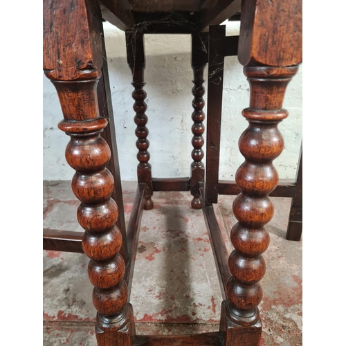 11 - An 18th century oak drop leaf gate leg dining table with bobbin turned supports - approx. 74cm high ... 