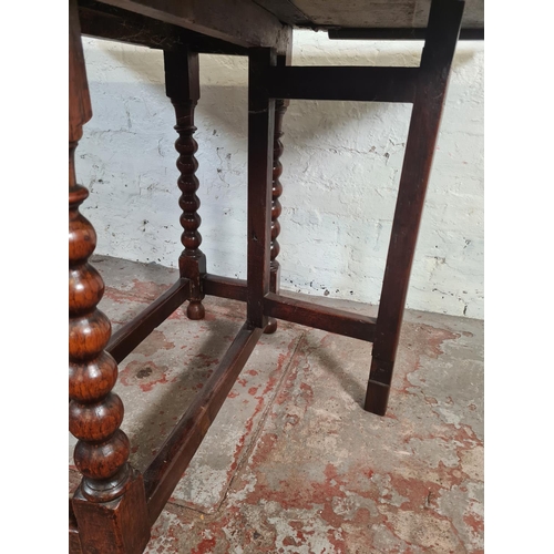 11 - An 18th century oak drop leaf gate leg dining table with bobbin turned supports - approx. 74cm high ... 