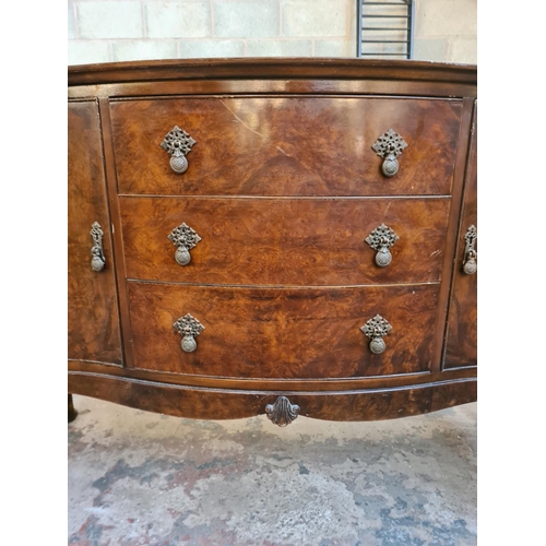 13 - A Regency style burr walnut serpentine sideboard with three drawers, two cupboard doors and cabriole... 