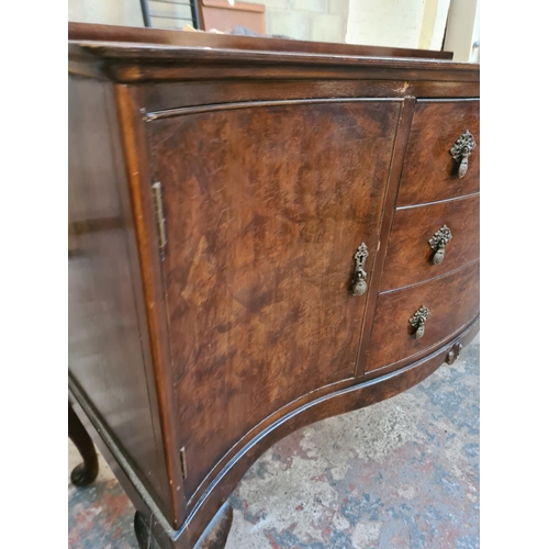 13 - A Regency style burr walnut serpentine sideboard with three drawers, two cupboard doors and cabriole... 