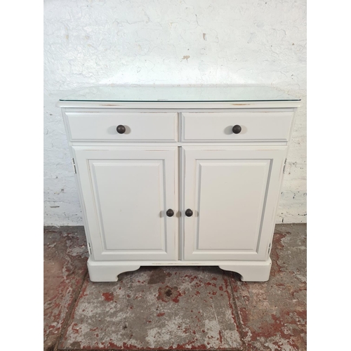 42 - A modern Ducal grey painted pine sideboard with two drawers, two cupboard doors and glass top - appr... 