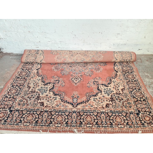 50 - A Persian style salmon pink and blue tasselled rug - approx. 286cm long x 200cm wide