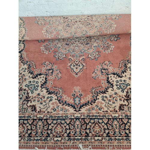 50 - A Persian style salmon pink and blue tasselled rug - approx. 286cm long x 200cm wide