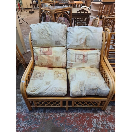 53 - A bamboo and cane three piece conservatory suite comprising two armchairs and three seater sofa