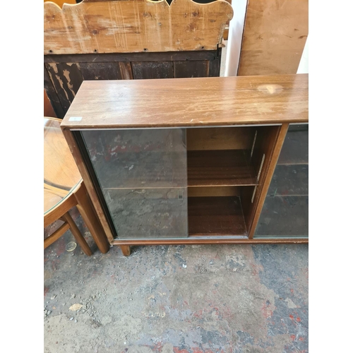 132 - A mid 20th century Minty mahogany bookcase with four glass sliding doors - approx. 86cm high x 154cm... 