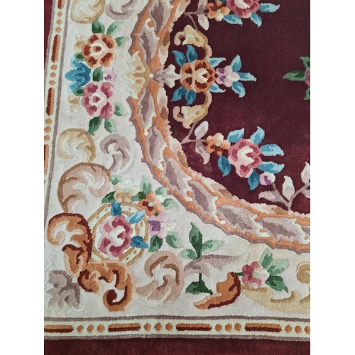 140A - A red floral patterned tasselled rug - approx. 210cm long x 130cm wide