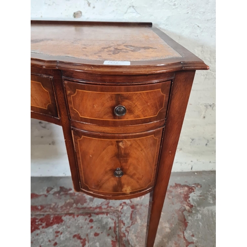 143I - A Regency style mahogany and tan leather serpentine writing desk with five drawers and tapering supp... 