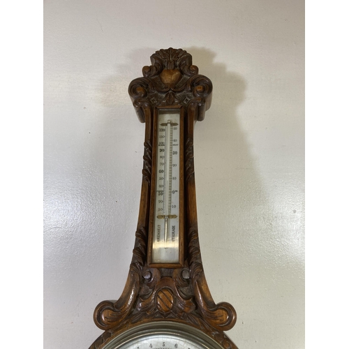 483 - An early 20th century Lloyd, Payne & Amiel of Manchester heavily carved oak barometer with porcelain... 