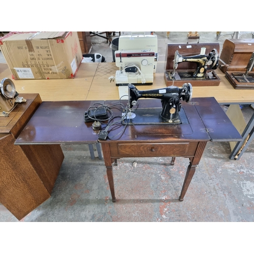 712 - A sewing machine table containing a Singer electric sewing machine with foot pedal