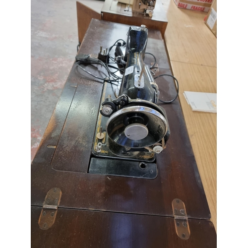 712 - A sewing machine table containing a Singer electric sewing machine with foot pedal