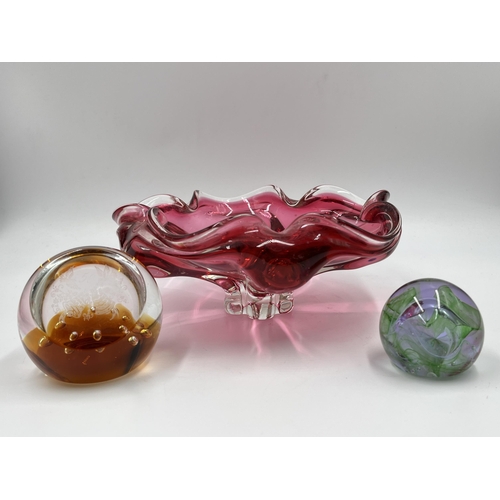 220 - Three pieces of studio glass, two Caithness paperweights and one cranberry glass bowl