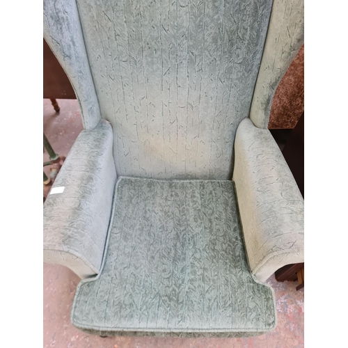 113 - A Victorian style green fabric upholstered wing back armchair with cabriole supports