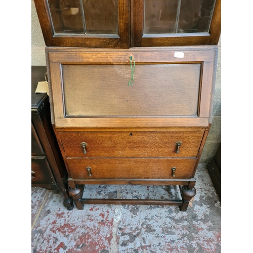 4 - A 1930s/40s oak bureau bookcase with two leaded glass doors, fall front, two drawers and baluster su... 