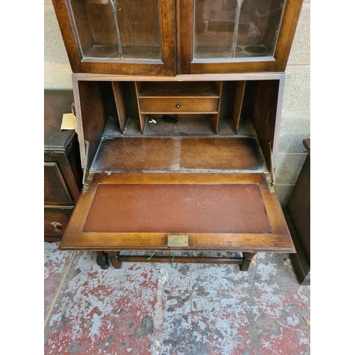 4 - A 1930s/40s oak bureau bookcase with two leaded glass doors, fall front, two drawers and baluster su... 