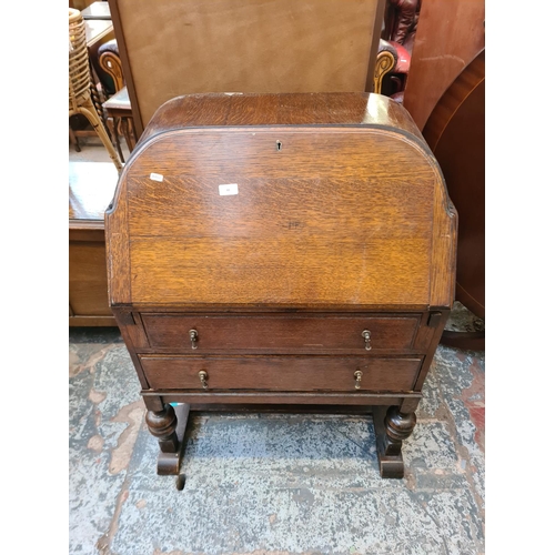 49 - An Art Deco oak bureau with fall front, two drawers and baluster supports