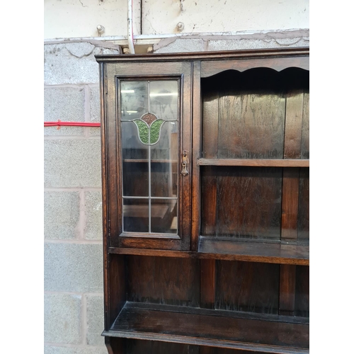 5 - A 1930s oak dresser with two stained and leaded glass doors and four drawers