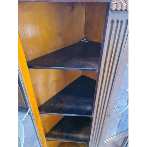 54 - An Art Deco style carved oak corner display cabinet with two leaded glass doors - approx. 149cm high... 