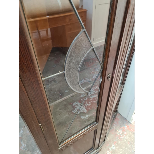 54 - An Art Deco style carved oak corner display cabinet with two leaded glass doors - approx. 149cm high... 