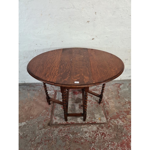 80 - An early 20th century oak drop leaf gate leg oval occasional table on barley twist supports - approx... 