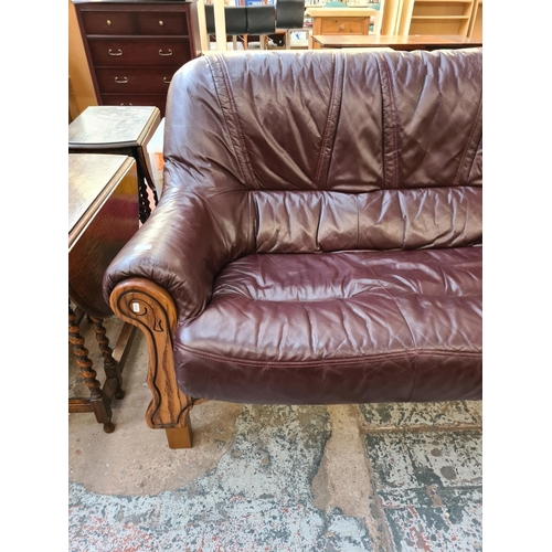 81 - A burgundy leather and carved oak three seater sofa - approx. 102cm high x 188cm wide x 87cm deep