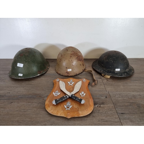 485 - Four items, three WWII helmets to include a Japanese Civil Defence helmet and one pair of kukri kniv... 