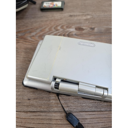 557 - A platinum silver Nintendo DS (NTR-001) original handheld games console with case and seventeen game... 