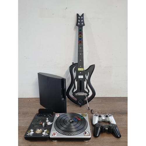 574 - A Sony PlayStation 3 slim games console with two DualShock 3 controllers, DJ HERO deck and Guitar He... 