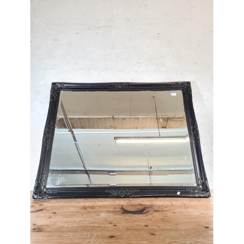 214 - A modern black painted framed bevelled edge wall mirror - approx. 115cm wide x 90cm high