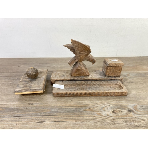 513 - An early 20th century carved wooden desk tidy with eagle top, inkwell, pen tray and matching ink blo... 