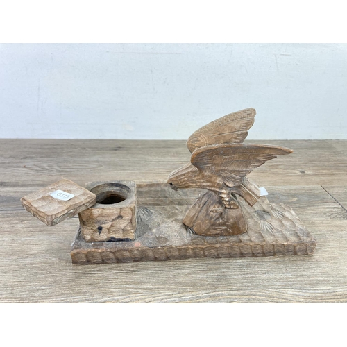 513 - An early 20th century carved wooden desk tidy with eagle top, inkwell, pen tray and matching ink blo... 