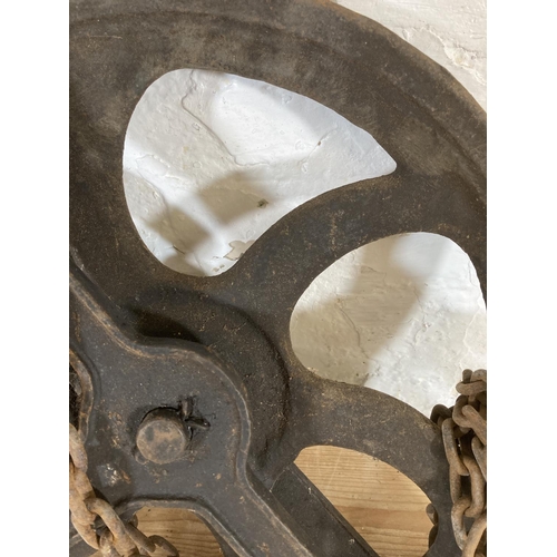 553 - A late 19th/early 20th century cast iron pulley wheel and chain - approx. 55cm high x 45cm wide