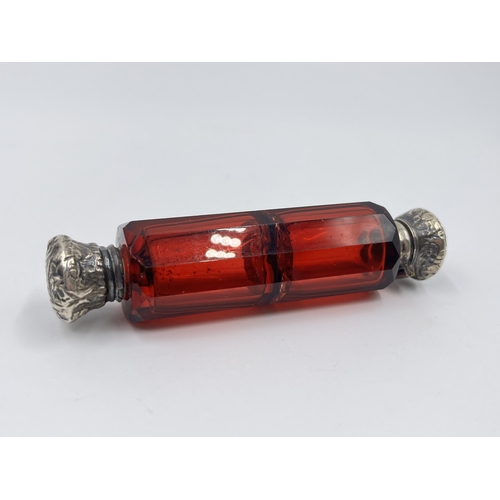 2253 - A Victorian dark cranberry glass double ended scent bottle with white metal tops - approx. 10cm long