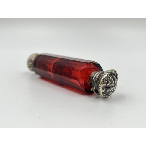 2253 - A Victorian dark cranberry glass double ended scent bottle with white metal tops - approx. 10cm long