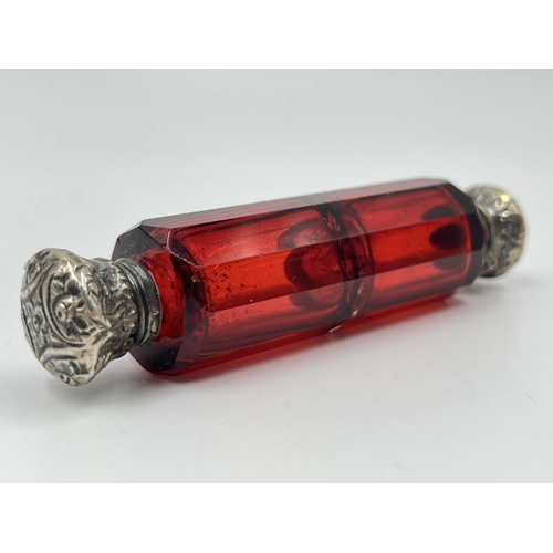 2253 - A Victorian dark cranberry glass double ended scent bottle with white metal tops - approx. 10cm long