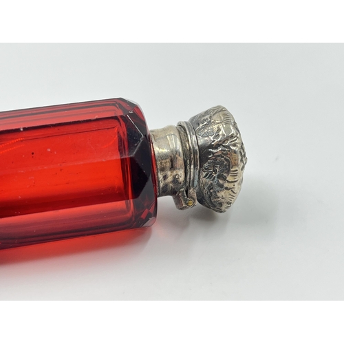 2253 - A Victorian dark cranberry glass double ended scent bottle with white metal tops - approx. 10cm long