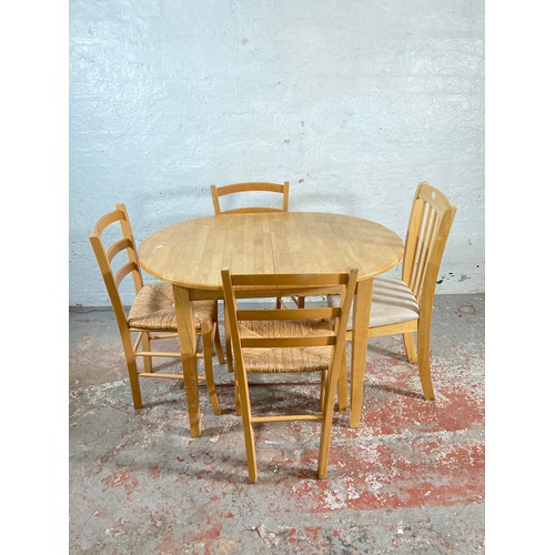 169 - A modern beech oval extending dining table and four dining chairs - approx. 134cm extended