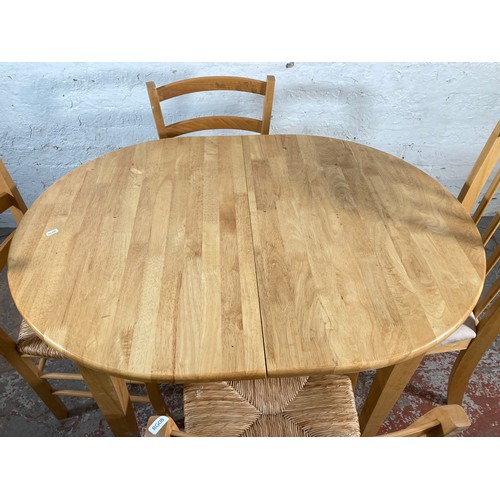 169 - A modern beech oval extending dining table and four dining chairs - approx. 134cm extended