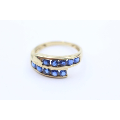 1053 - A 9ct gold sapphire channel set bypass ring, size P - approx. gross weight 2.6 grams