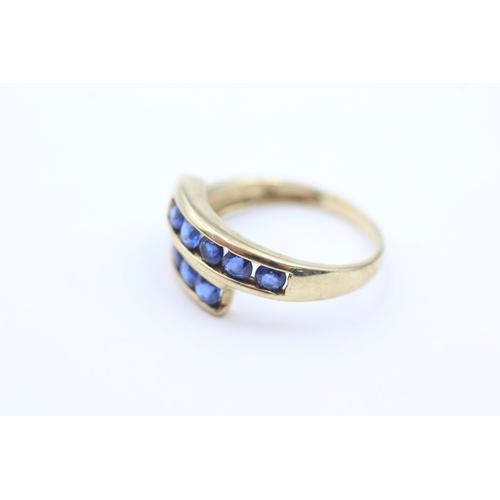 1053 - A 9ct gold sapphire channel set bypass ring, size P - approx. gross weight 2.6 grams