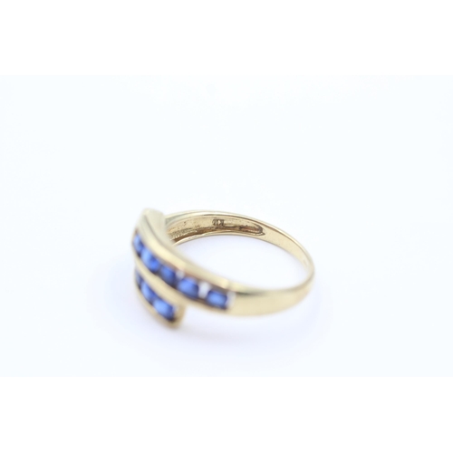 1053 - A 9ct gold sapphire channel set bypass ring, size P - approx. gross weight 2.6 grams