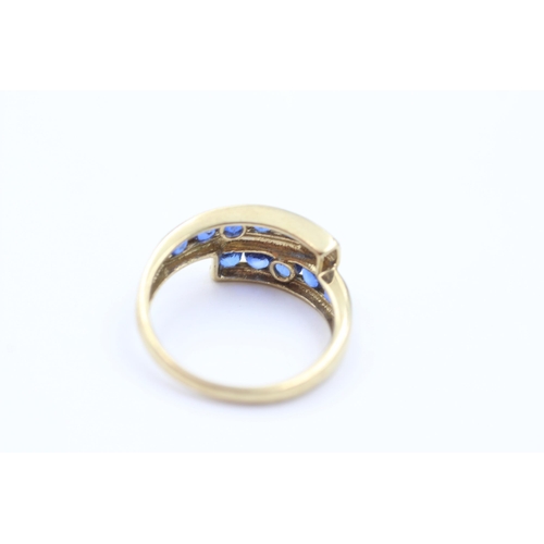 1053 - A 9ct gold sapphire channel set bypass ring, size P - approx. gross weight 2.6 grams