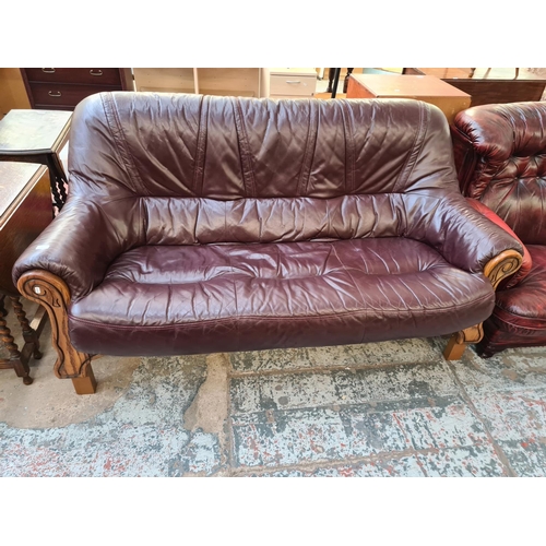 69 - A burgundy leather and carved oak three seater sofa - approx. 102cm high x 188cm wide x 87cm deep