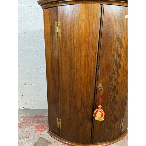 34 - A George III style oak wall mountable corner cabinet with brass 'H' hinges - approx. 90cm high x 67c... 