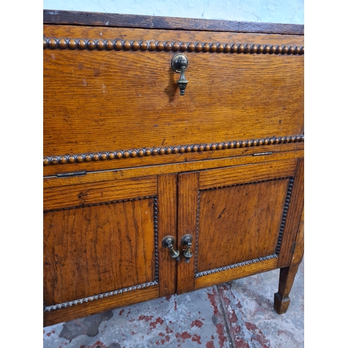 117 - A 1930s oak cabinet with fall front, two lower cupboard doors and beaded decoration - approx. 66cm h... 