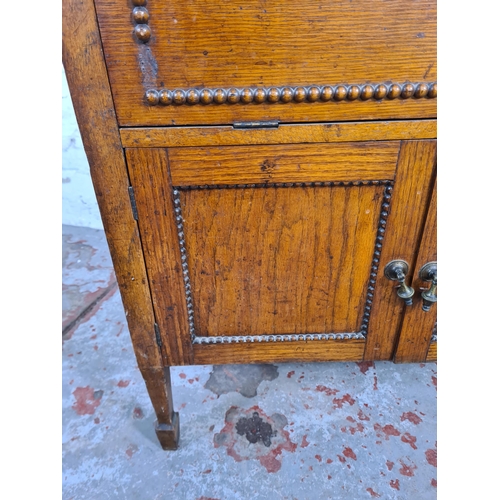 117 - A 1930s oak cabinet with fall front, two lower cupboard doors and beaded decoration - approx. 66cm h... 