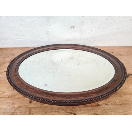 171 - An early 20th century oak framed bevelled edge oval wall mirror - approx. 90cm wide x 65cm high