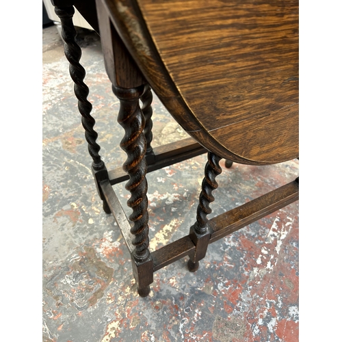 134 - An early 20th century oak drop leaf gate legged oval occasional table on barley twist supports - app... 